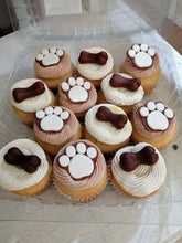 Brown paw and bone cupcakes displayed in a clear container, perfect for celebrating pets.