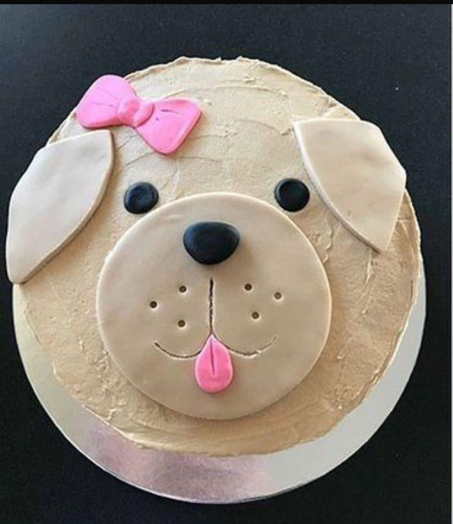 Adorable puppy face cake with floppy ears and pink bow, perfect for celebrating your dog's special day.