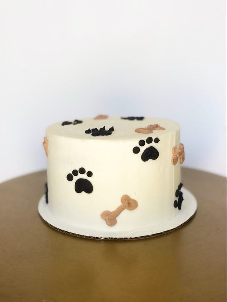 TPS Signature Paw Cake featuring black and tan paw and bone decorations on a minimalist white cake.