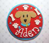 Handcrafted dog face cake topper with paw prints and bones for pet celebrations, personalized with name Aden.