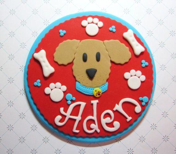 Handcrafted dog face cake topper with paw prints and bones for pet celebrations, personalized with name Aden.