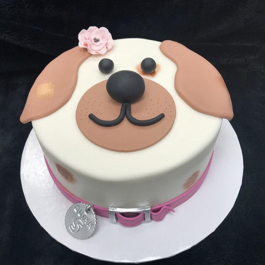 Cute pink pup celebration cake featuring dog face design and flower decoration, perfect for pet birthdays.